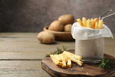 Photo of Tasty french fries with rosemary on wooden table, closeup. Space for text