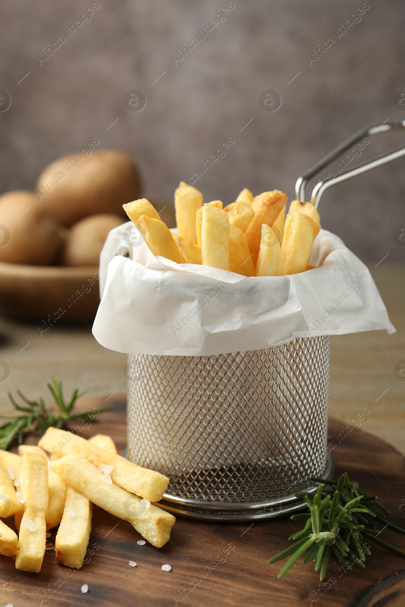 Tasty french fries with rosemary on wooden table, closeup Photo of Tasty french fries with rosemary on wooden table, closeup
