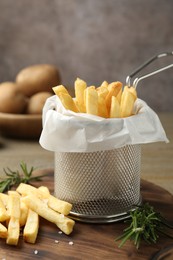 Photo of Tasty french fries with rosemary on wooden table, closeup
