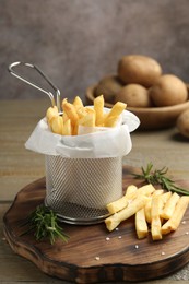 Photo of Tasty french fries with rosemary on wooden table, closeup