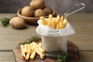 Photo of Tasty french fries with rosemary on wooden table, closeup