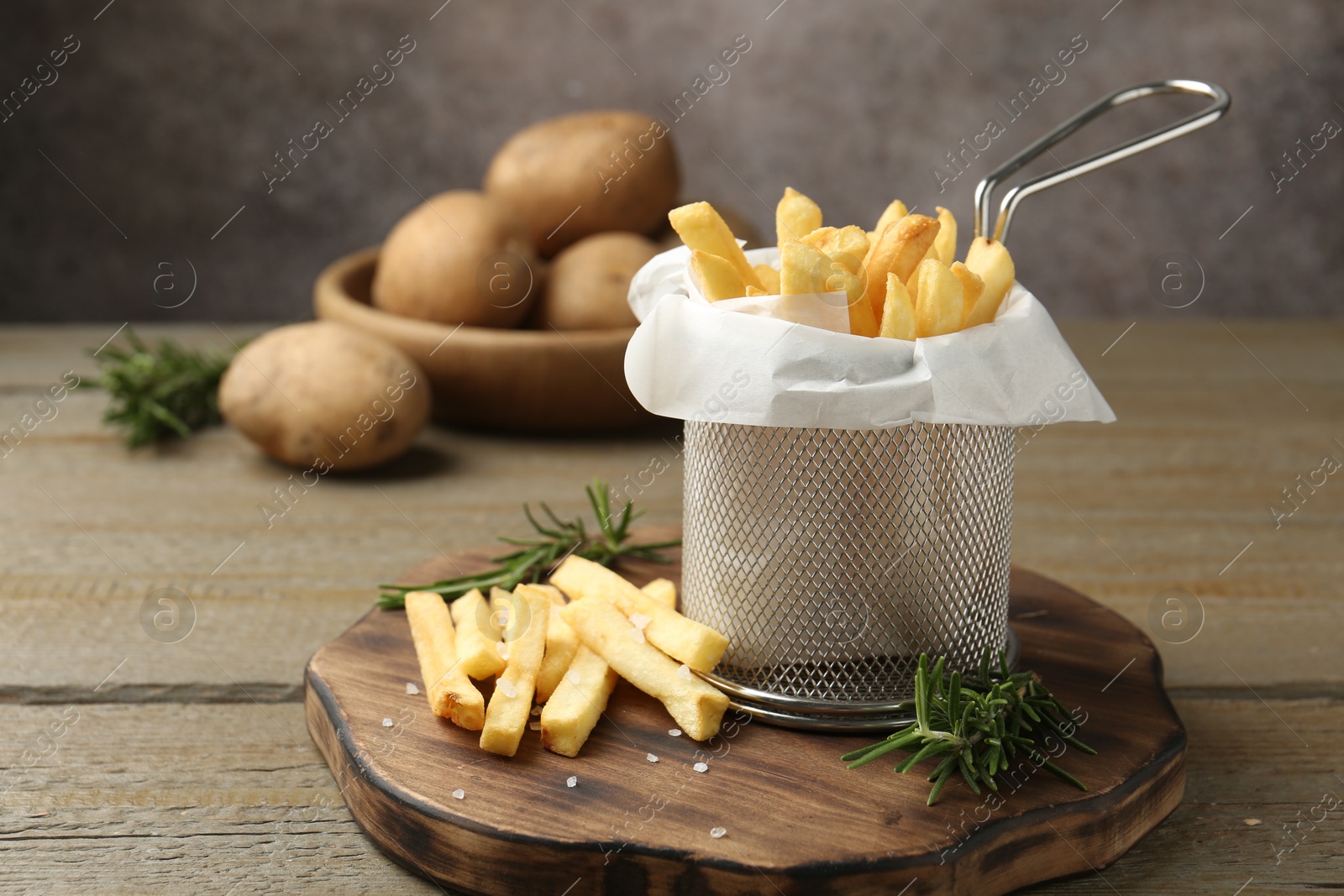 Tasty french fries with rosemary on wooden table, closeup Photo of Tasty french fries with rosemary on wooden table, closeup