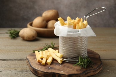 Photo of Tasty french fries with rosemary on wooden table, closeup