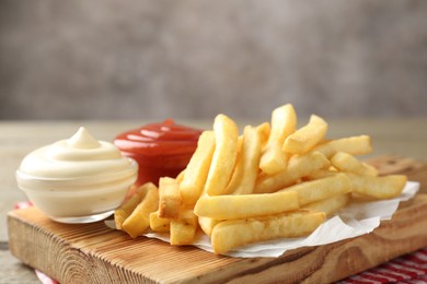 Photo of Tasty french fries with sauces on wooden table, closeup. Space for text