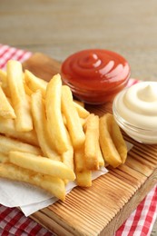 Photo of Tasty french fries with sauces on wooden table, closeup