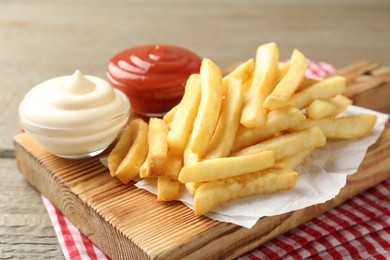 Photo of Tasty french fries with sauces on wooden table, closeup