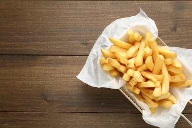 Photo of Tasty french fries on wooden table, top view. Space for text