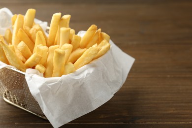 Photo of Tasty french fries on wooden table, closeup. Space for text