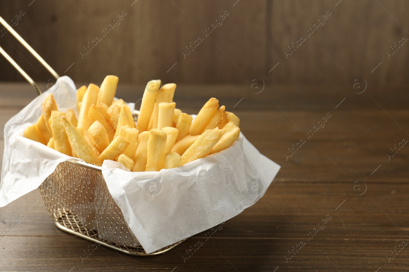 Photo of Tasty french fries on wooden table, closeup. Space for text