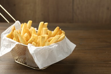 Photo of Tasty french fries on wooden table, closeup. Space for text