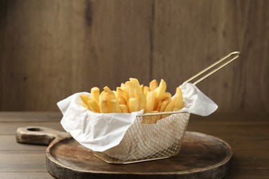 Photo of Fresh tasty french fries on wooden table. Space for text