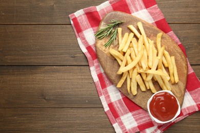 Photo of Tasty french fries with ketchup and rosemary on wooden table, top view. Space for text