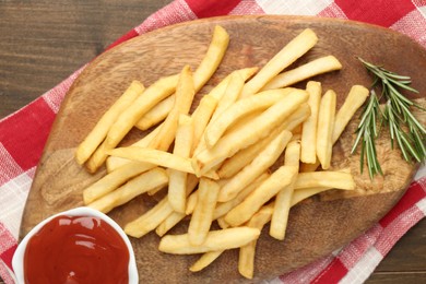 Photo of Tasty french fries with ketchup and rosemary on wooden table, top view