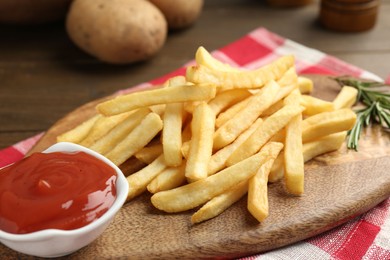 Photo of Tasty french fries with ketchup and rosemary on wooden table, closeup