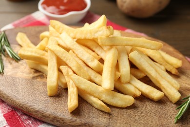 Photo of Tasty french fries with rosemary on wooden table, closeup