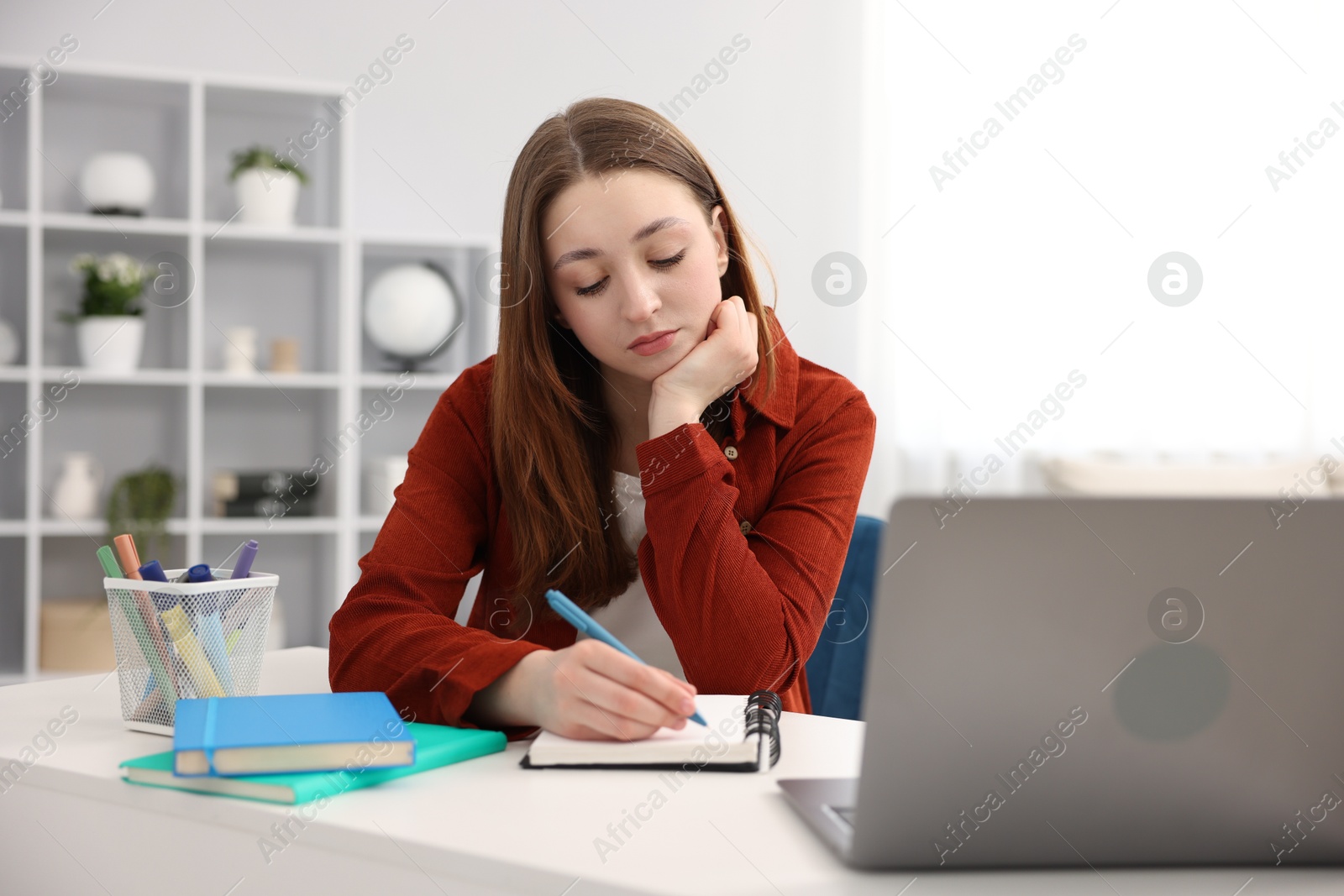 Teenage girl doing homework at table indoors Photo of Teenage girl doing homework at table indoors