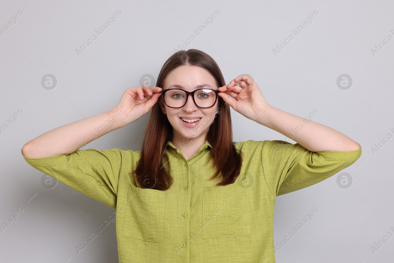 Photo of Happy teenage girl in glasses on light grey background