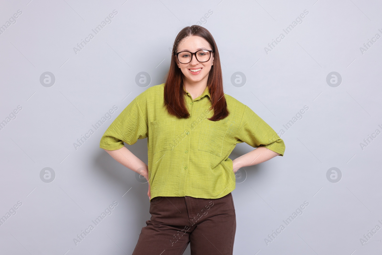 Photo of Happy teenage girl in glasses on light grey background