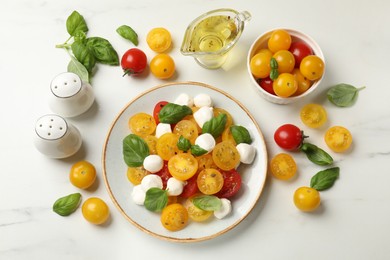 Photo of Fresh salad with yellow tomatoes, basil and mozzarella cheese on white marble table, flat lay