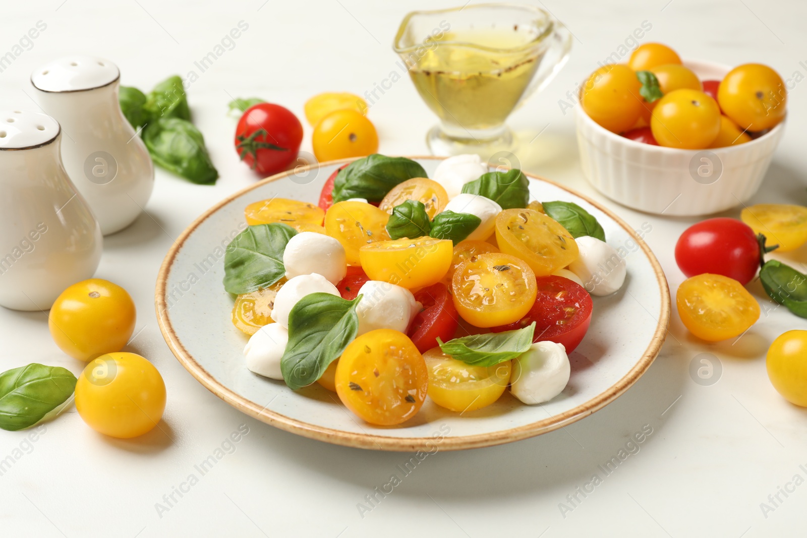 Fresh salad with yellow tomatoes, basil and mozzarella cheese on white marble table, closeup Photo of Fresh salad with yellow tomatoes, basil and mozzarella cheese on white marble table, closeup