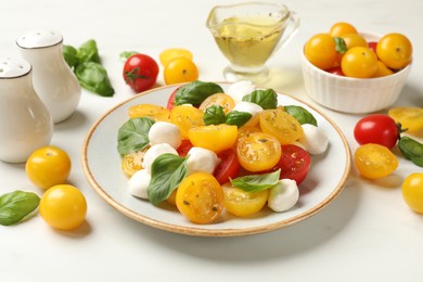 Photo of Fresh salad with yellow tomatoes, basil and mozzarella cheese on white marble table, closeup