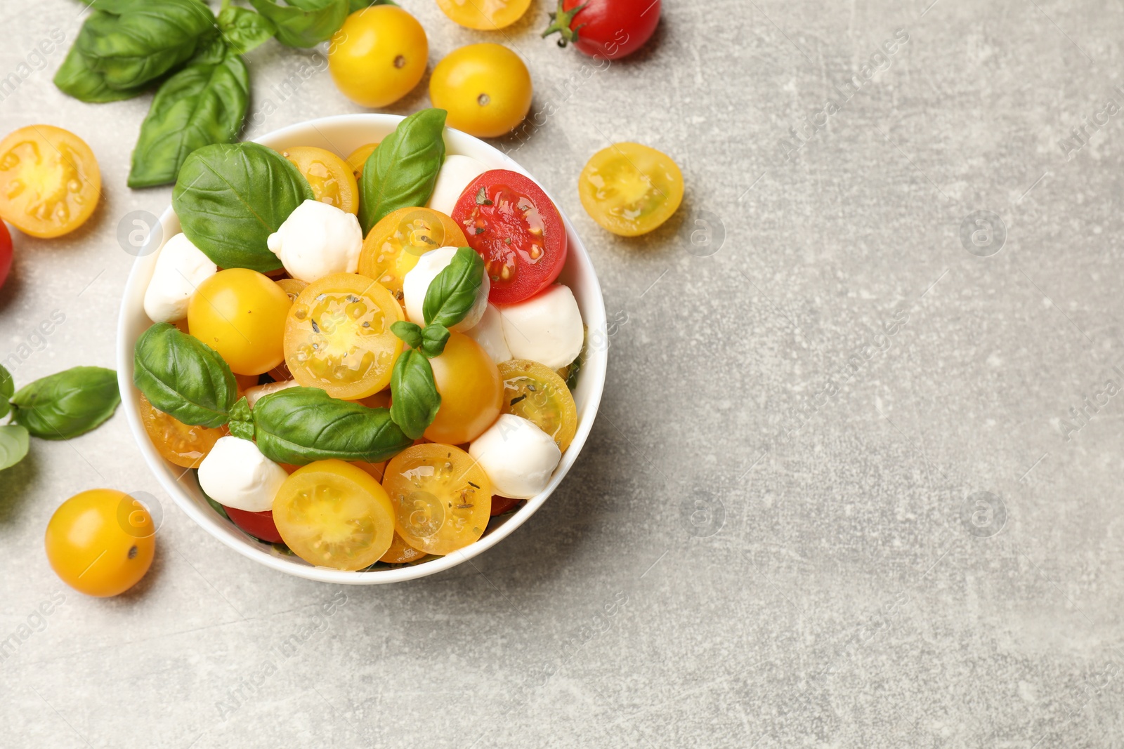 Fresh salad with yellow tomatoes, basil and mozzarella cheese on grey table, flat lay. Space for text Photo of Fresh salad with yellow tomatoes, basil and mozzarella cheese on grey table, flat lay. Space for text