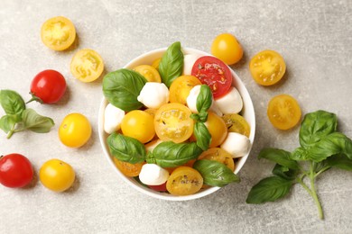 Photo of Fresh salad with yellow tomatoes, basil and mozzarella cheese on grey table, flat lay