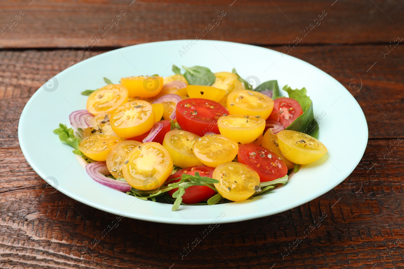Fresh salad with yellow tomatoes on wooden table, closeup Photo of Fresh salad with yellow tomatoes on wooden table, closeup