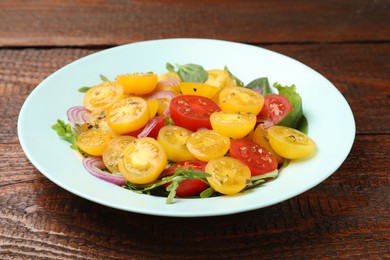 Photo of Fresh salad with yellow tomatoes on wooden table, closeup