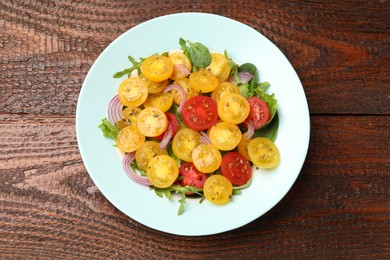 Photo of Fresh salad with yellow tomatoes on wooden table, top view