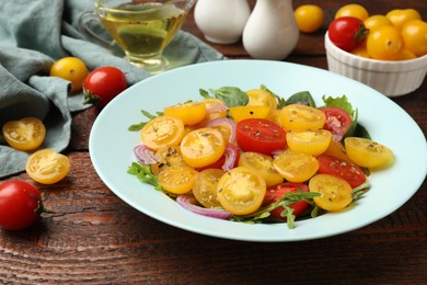 Photo of Fresh salad with yellow tomatoes served on wooden table, closeup