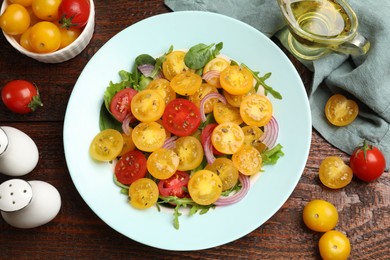 Photo of Fresh salad with yellow tomatoes served on wooden table, flat lay