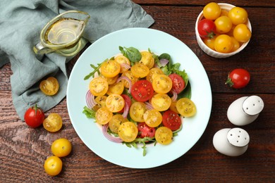 Photo of Fresh salad with yellow tomatoes served on wooden table, flat lay