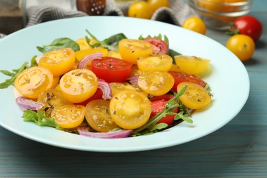 Photo of Fresh salad with yellow tomatoes on light blue wooden table, closeup