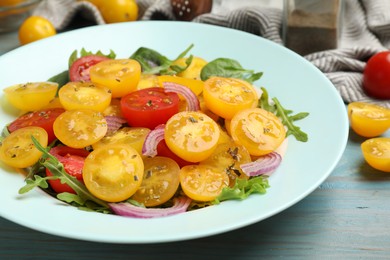 Photo of Fresh salad with yellow tomatoes on light blue wooden table, closeup