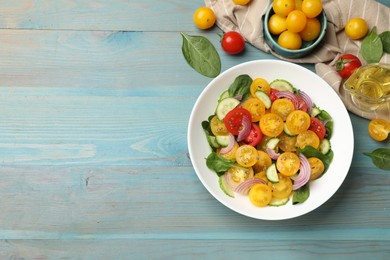 Photo of Fresh salad with yellow tomatoes served on light blue wooden table, flat lay. Space for text