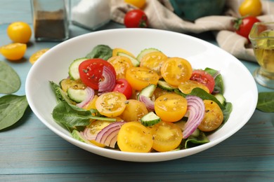 Photo of Fresh salad with yellow tomatoes served on light blue wooden table, closeup