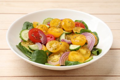 Photo of Fresh salad with yellow tomatoes on wooden table, closeup