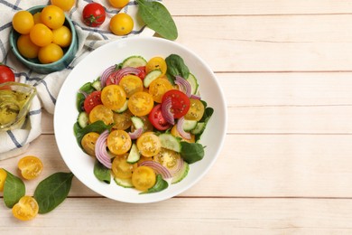 Photo of Fresh salad with yellow tomatoes served on wooden table, flat lay. Space for text