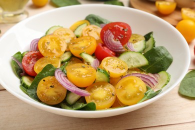 Photo of Fresh salad with yellow tomatoes on wooden table, closeup