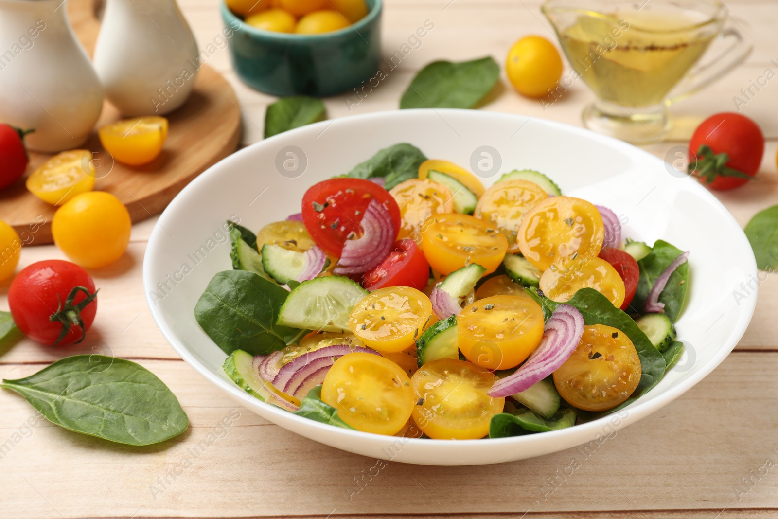 Fresh salad with yellow tomatoes served on wooden table, closeup Photo of Fresh salad with yellow tomatoes served on wooden table, closeup