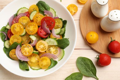 Photo of Fresh salad with yellow tomatoes served on wooden table, flat lay