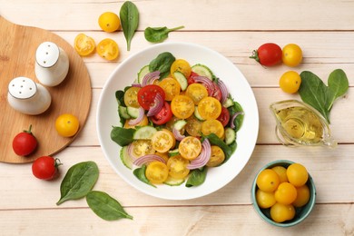 Photo of Fresh salad with yellow tomatoes served on wooden table, flat lay