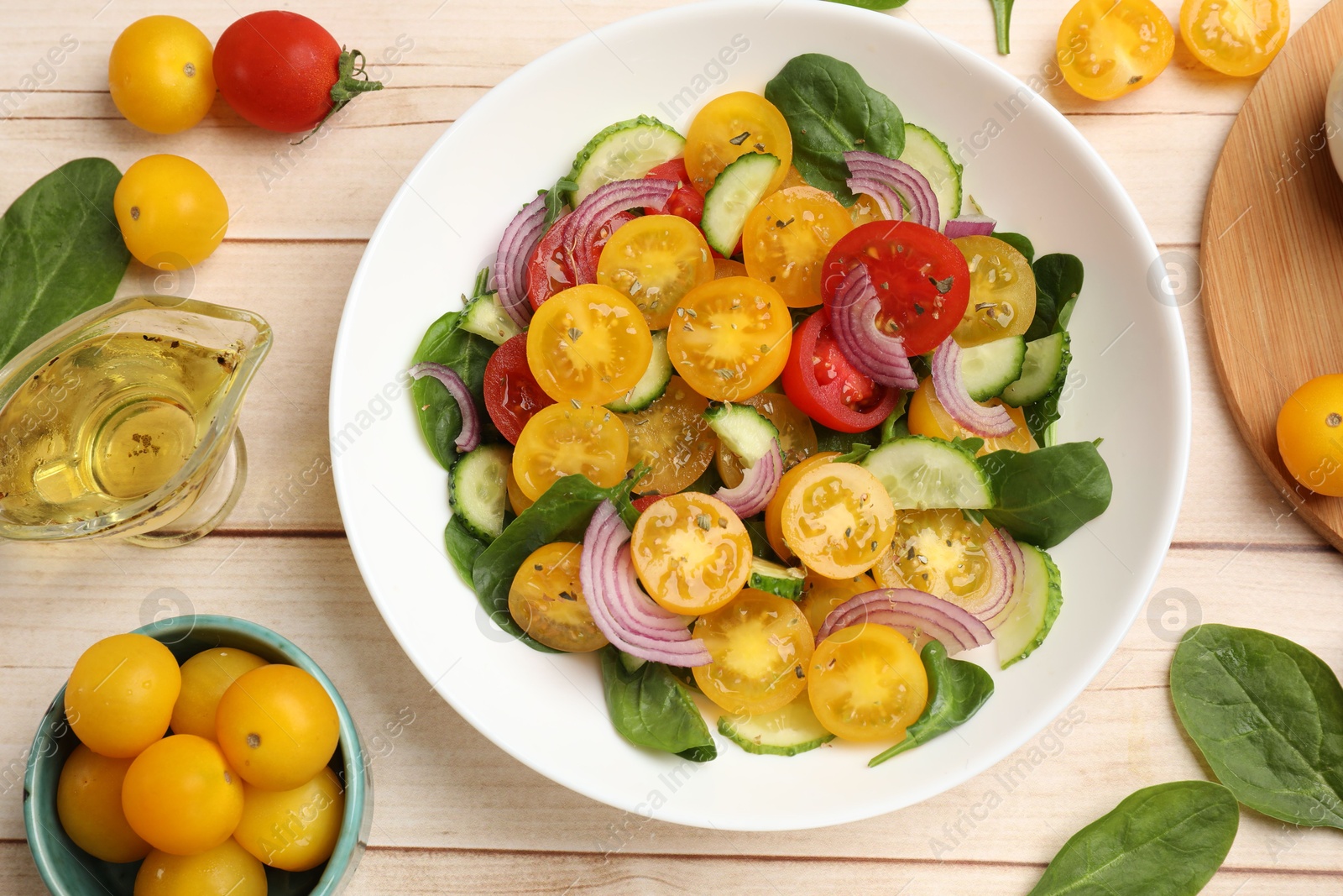 Fresh salad with yellow tomatoes served on wooden table, flat lay Photo of Fresh salad with yellow tomatoes served on wooden table, flat lay