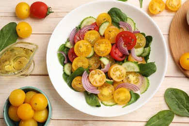 Photo of Fresh salad with yellow tomatoes served on wooden table, flat lay