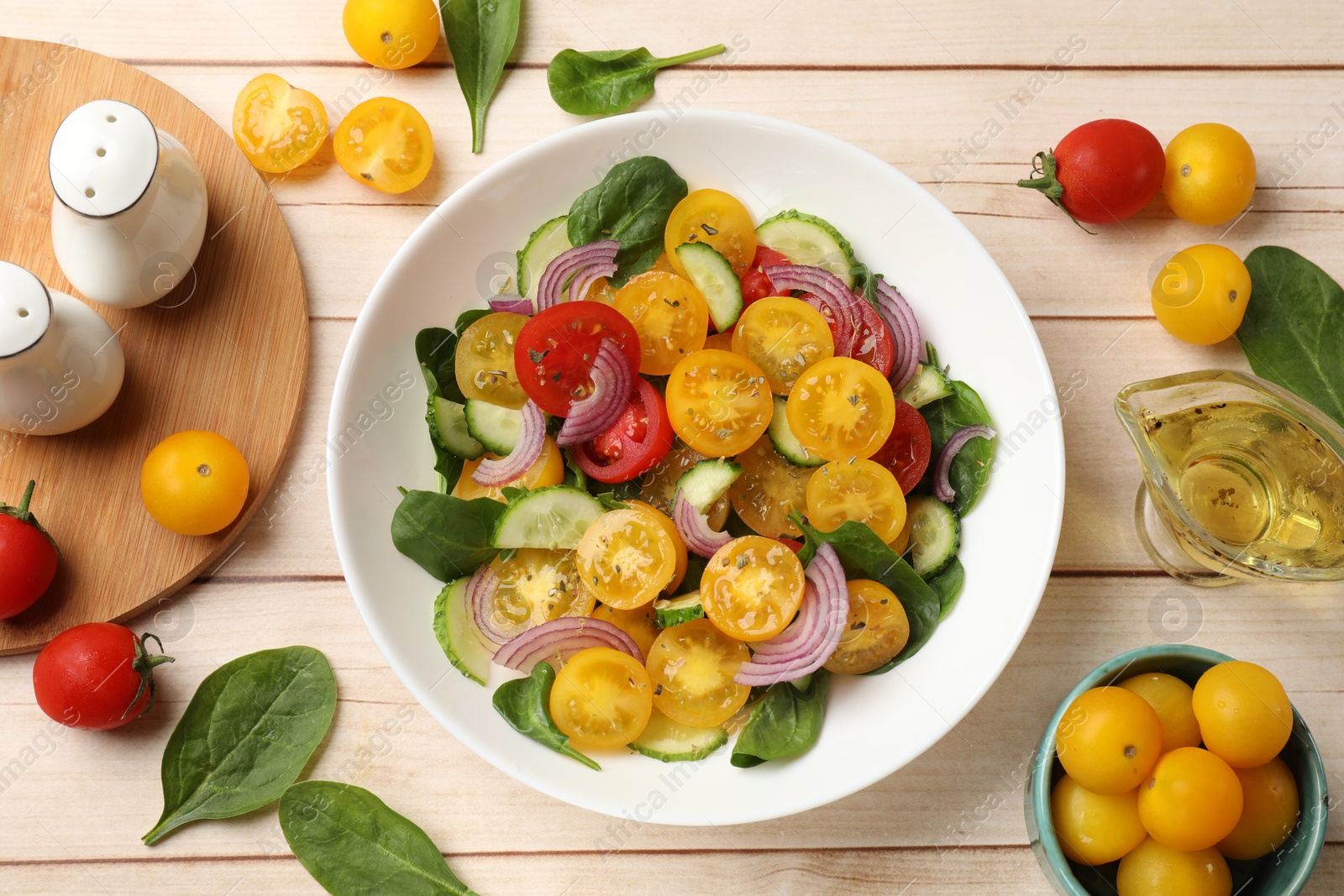 Fresh salad with yellow tomatoes served on wooden table, flat lay Photo of Fresh salad with yellow tomatoes served on wooden table, flat lay