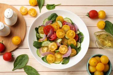 Photo of Fresh salad with yellow tomatoes served on wooden table, flat lay