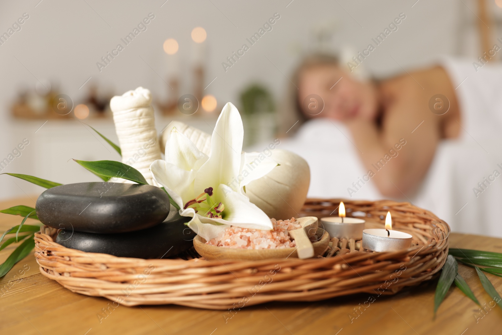 Senior woman relaxing on massage couch indoors, selective focus. Different spa products and lily flower on table Photo of Senior woman relaxing on massage couch indoors, selective focus. Different spa products and lily flower on table