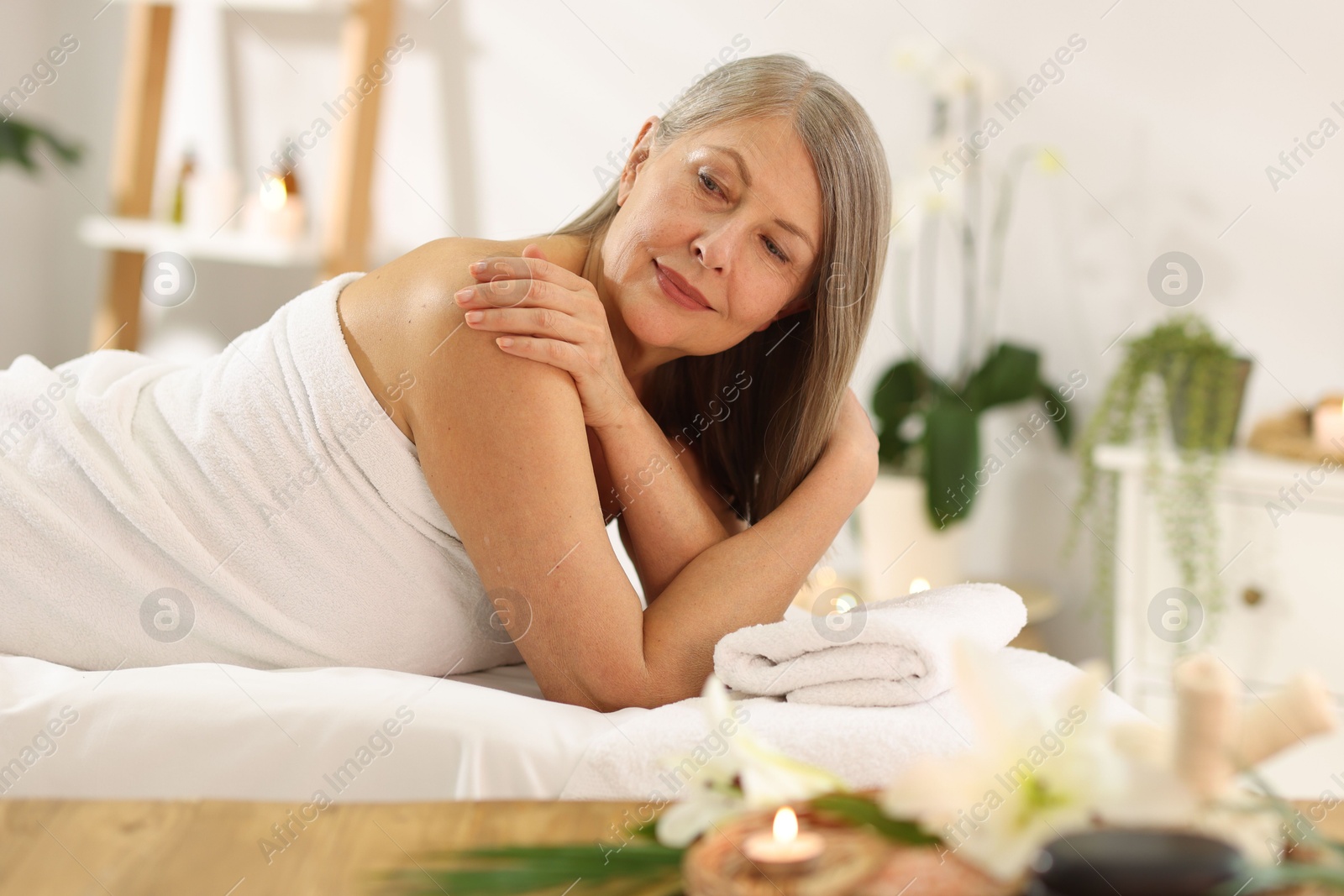 Senior woman relaxing on massage couch in spa salon Photo of Senior woman relaxing on massage couch in spa salon