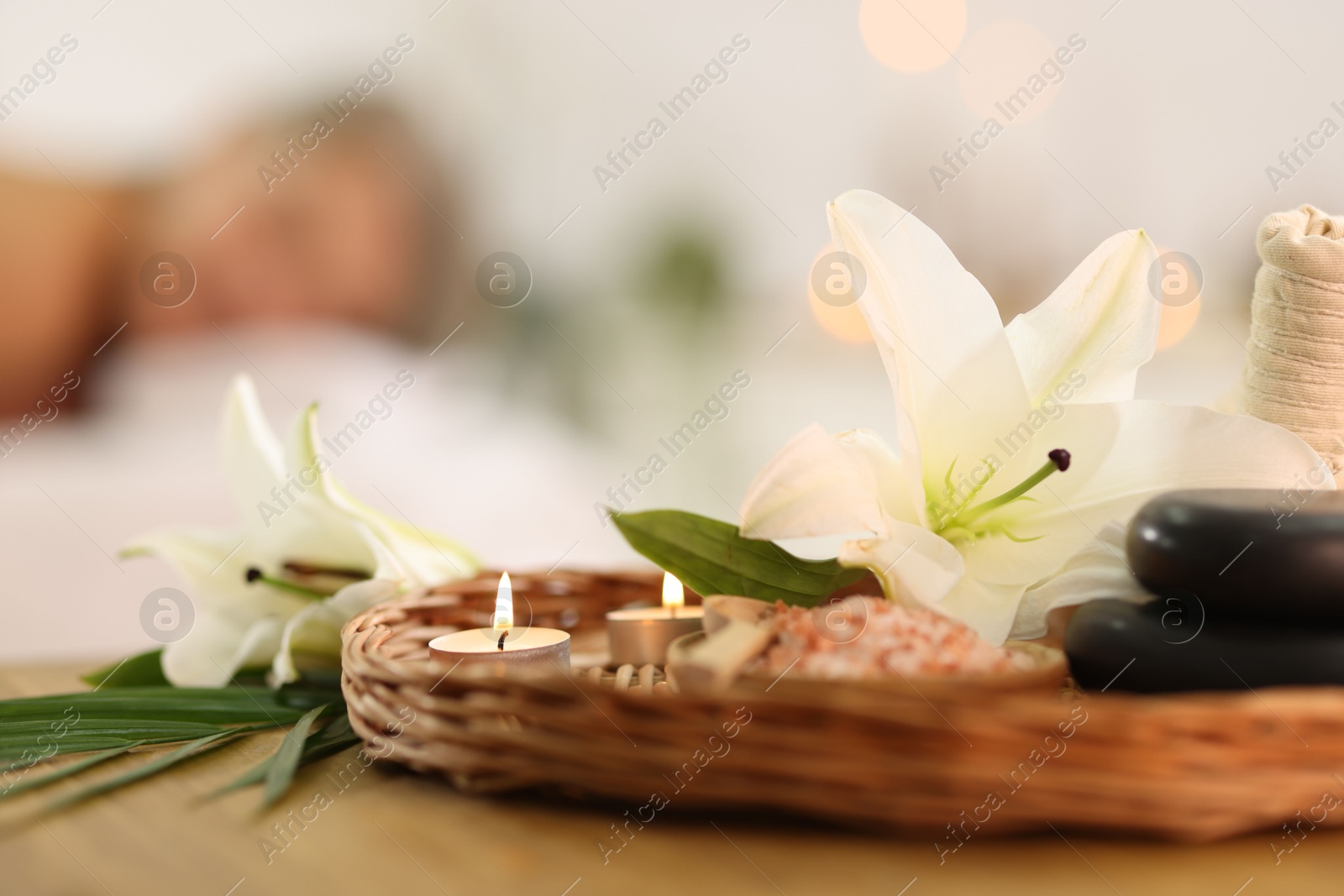 Senior woman relaxing on massage couch indoors, selective focus. Different spa products and lily flowers on table Photo of Senior woman relaxing on massage couch indoors, selective focus. Different spa products and lily flowers on table
